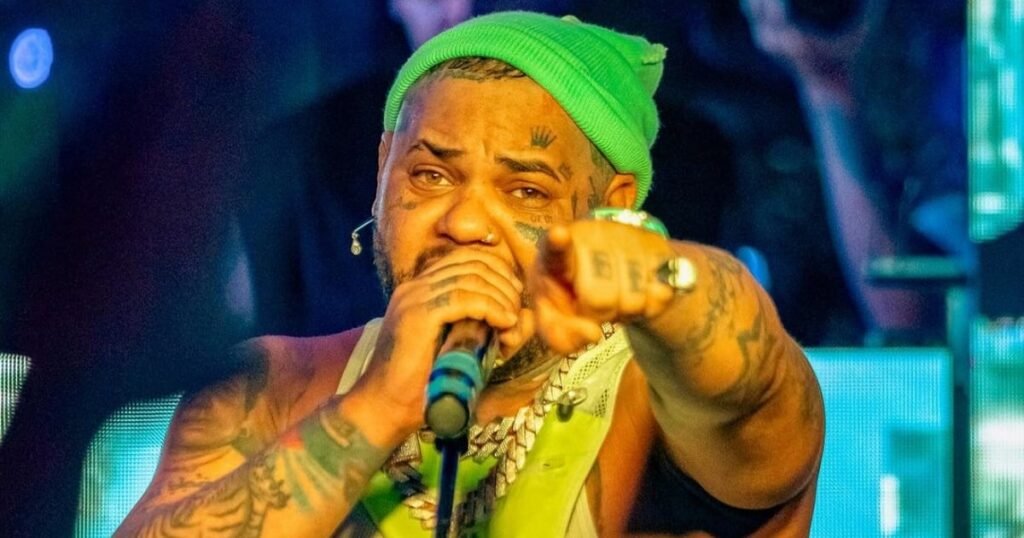 Imagen de El Taiger en un escenario, anunciando el lanzamiento de sus canciones inéditas póstumas.