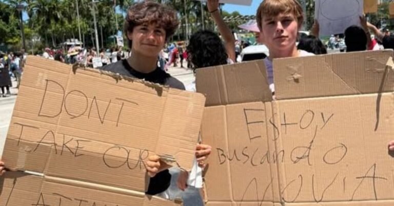 Dos adolescentes en una protesta en Miami sostienen carteles virales que dicen 'No se lleven a nuestras latinas' y 'Estoy buscando novia'.