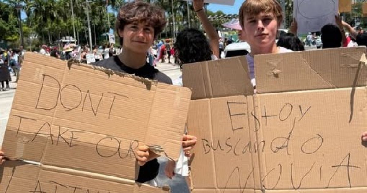 Dos adolescentes en una protesta en Miami sostienen carteles virales que dicen 'No se lleven a nuestras latinas' y 'Estoy buscando novia'.