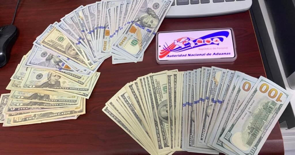 Un oficial de aduanas inspecciona fajos de dólares en el Aeropuerto de Panamá, tras la retención de miles de dólares a una ciudadana cubana.