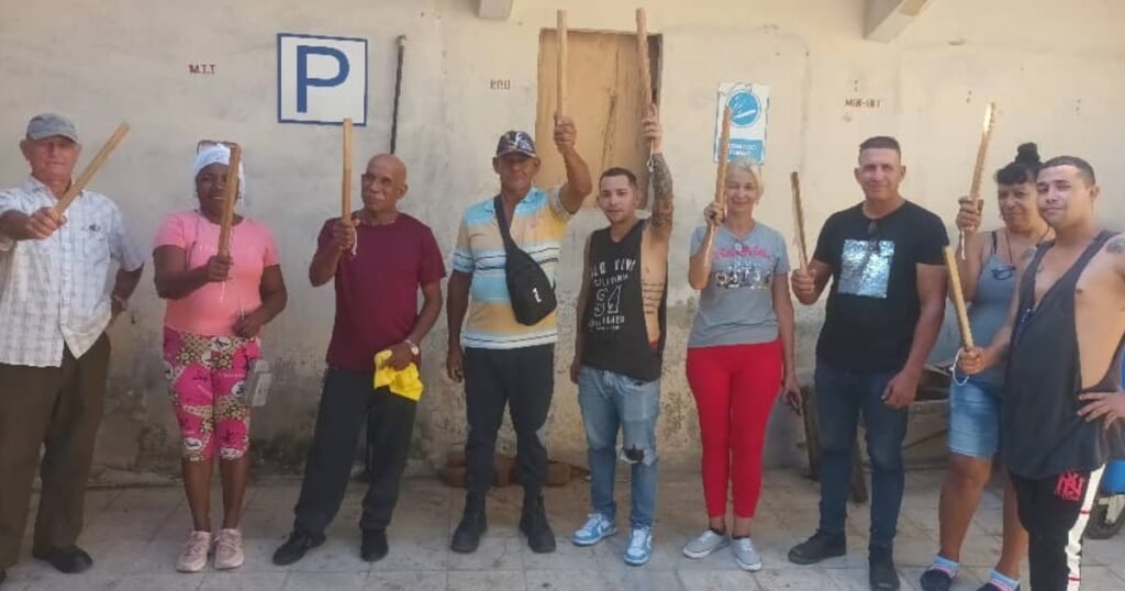 Civiles cubanos participan en ejercicios del Día de la Defensa con grandes palos de madera, cuestionando el poderío militar cubano.