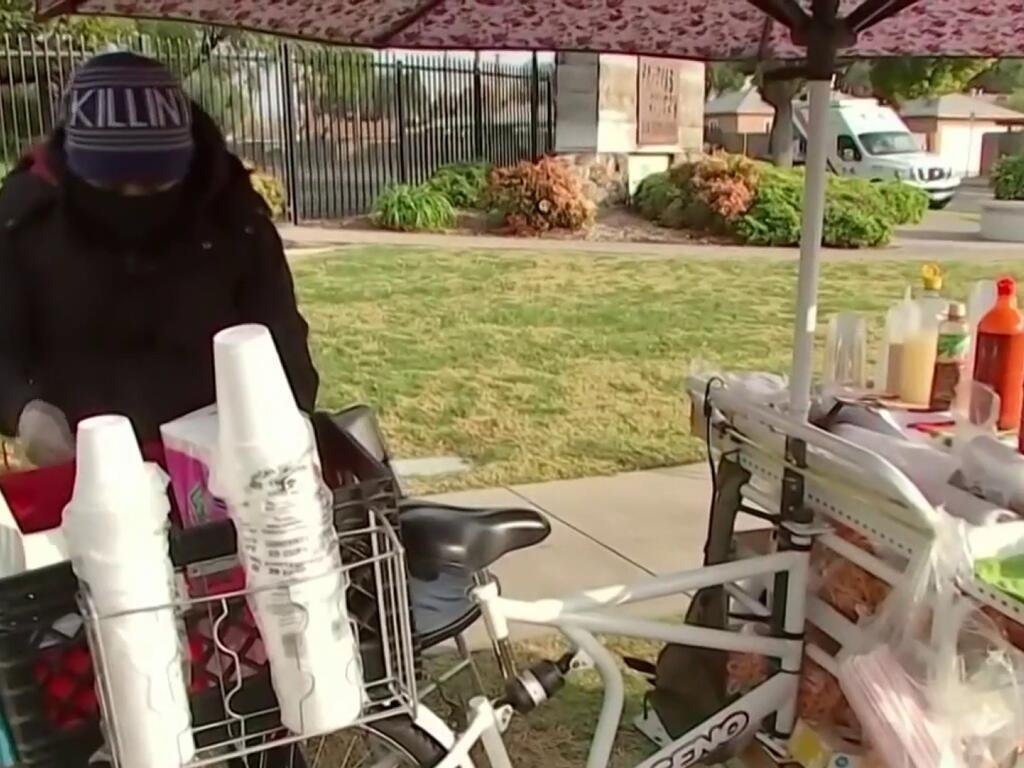 Un activista entrega dinero a un vendedor ambulante de fruta en la calle para protegerlo de ICE.