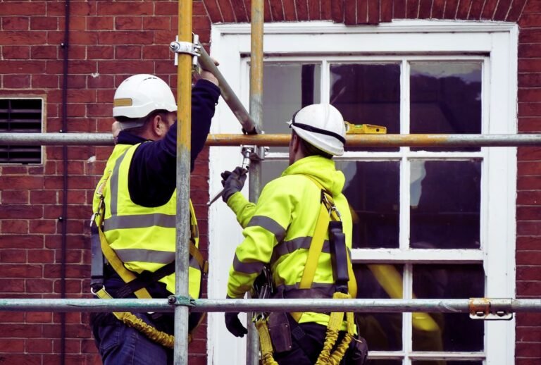 Obreros de la construcción trabajando en un andamio, representando la mano de obra afectada por las redadas de ICE.
