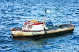 Una pequeña y rústica barca de pesca en la orilla del mar en Cuba, con el sol poniéndose al fondo, simbolizando la pesca de subsistencia.