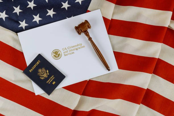 Una mano sosteniendo un pasaporte estadounidense frente a un mazo de juez, simbolizando la revocación de ciudadanía estadounidense.